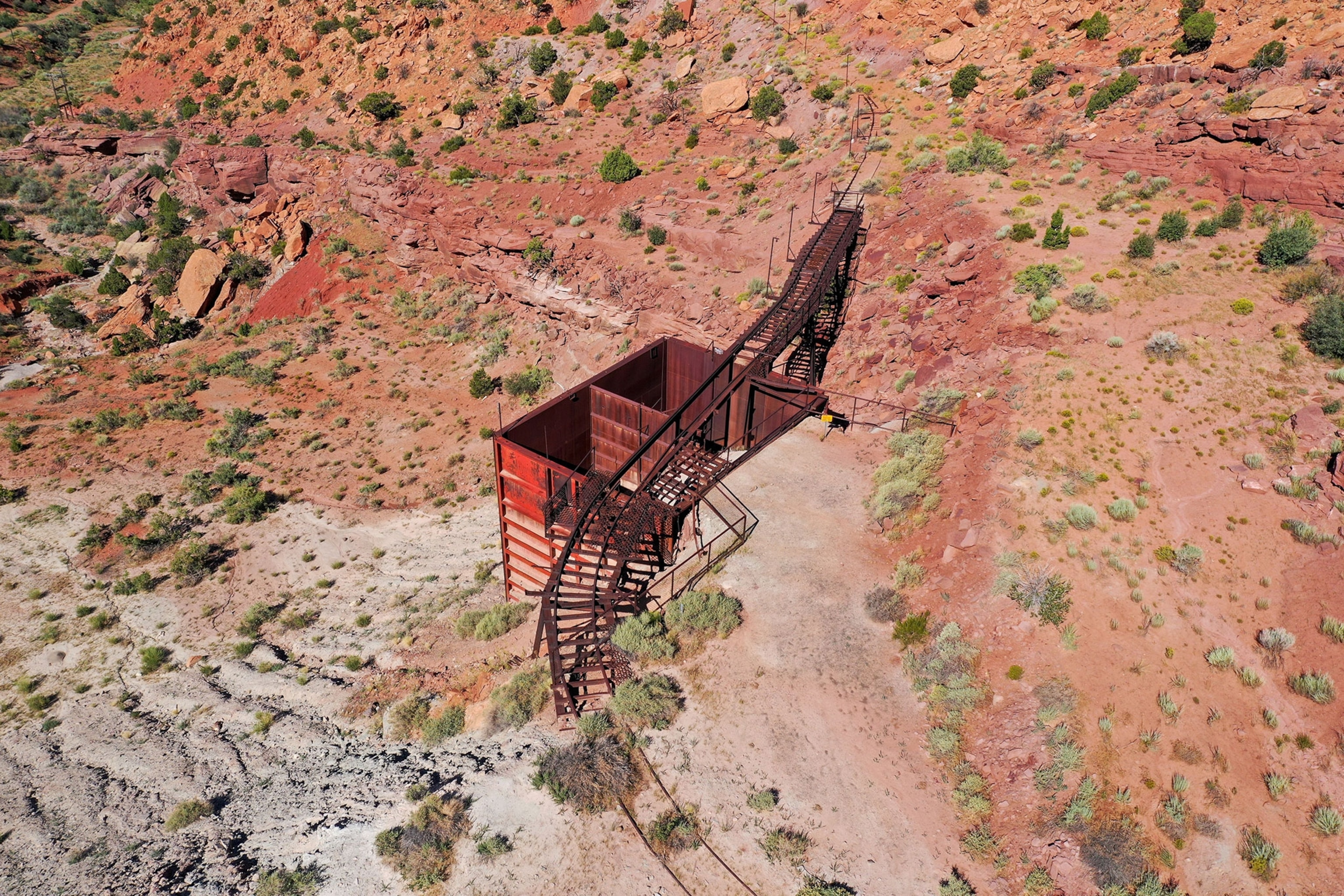 A rusty, abandoned, ore bin on the side of a reddish, dessert rocky mountain side Steen Canyon near La Sal, Utah