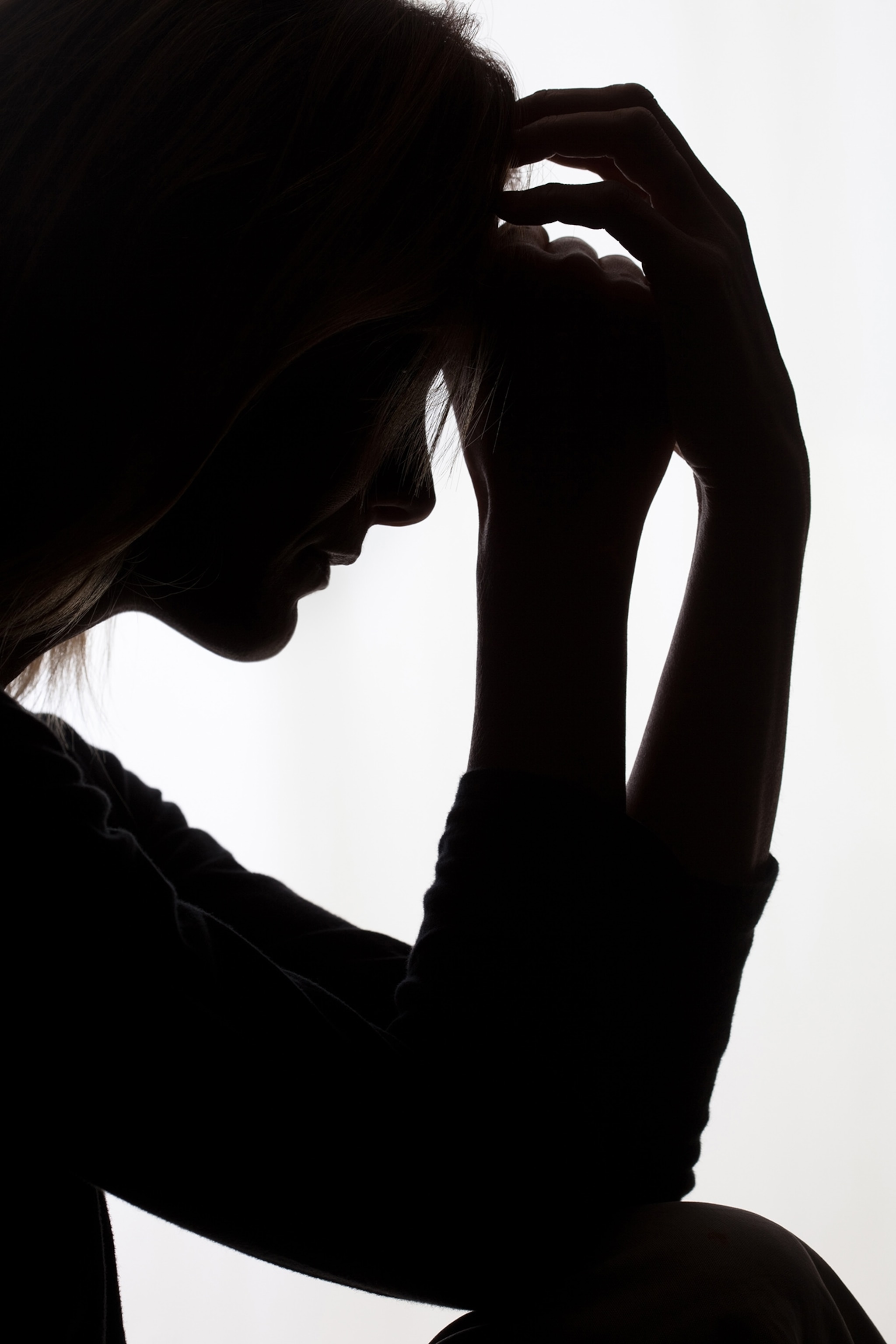 Silhouette of a woman with head in hands.