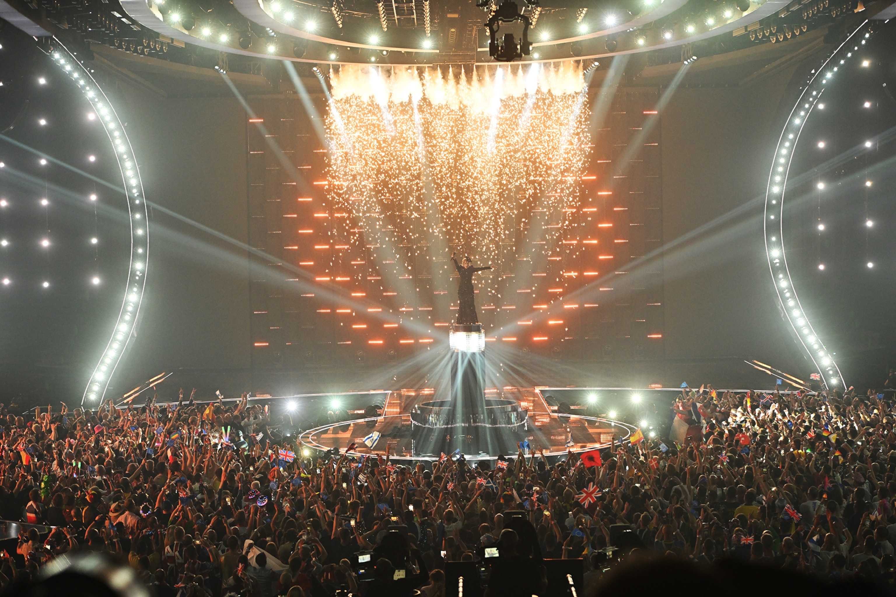 A performer surrounded by lights and on a high platform during their performance.