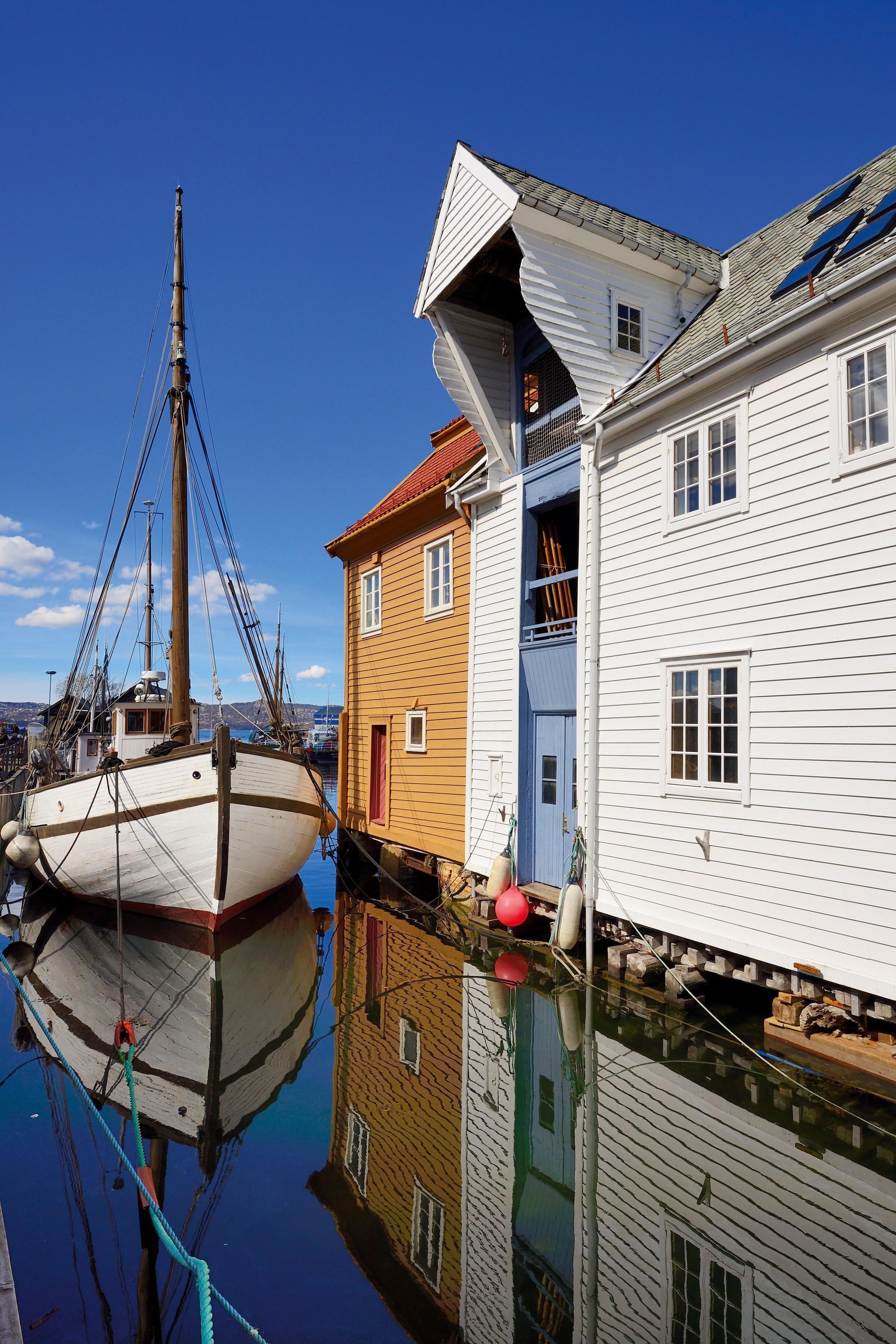 A traditional sailing boat in a canal by a row of wooden houses