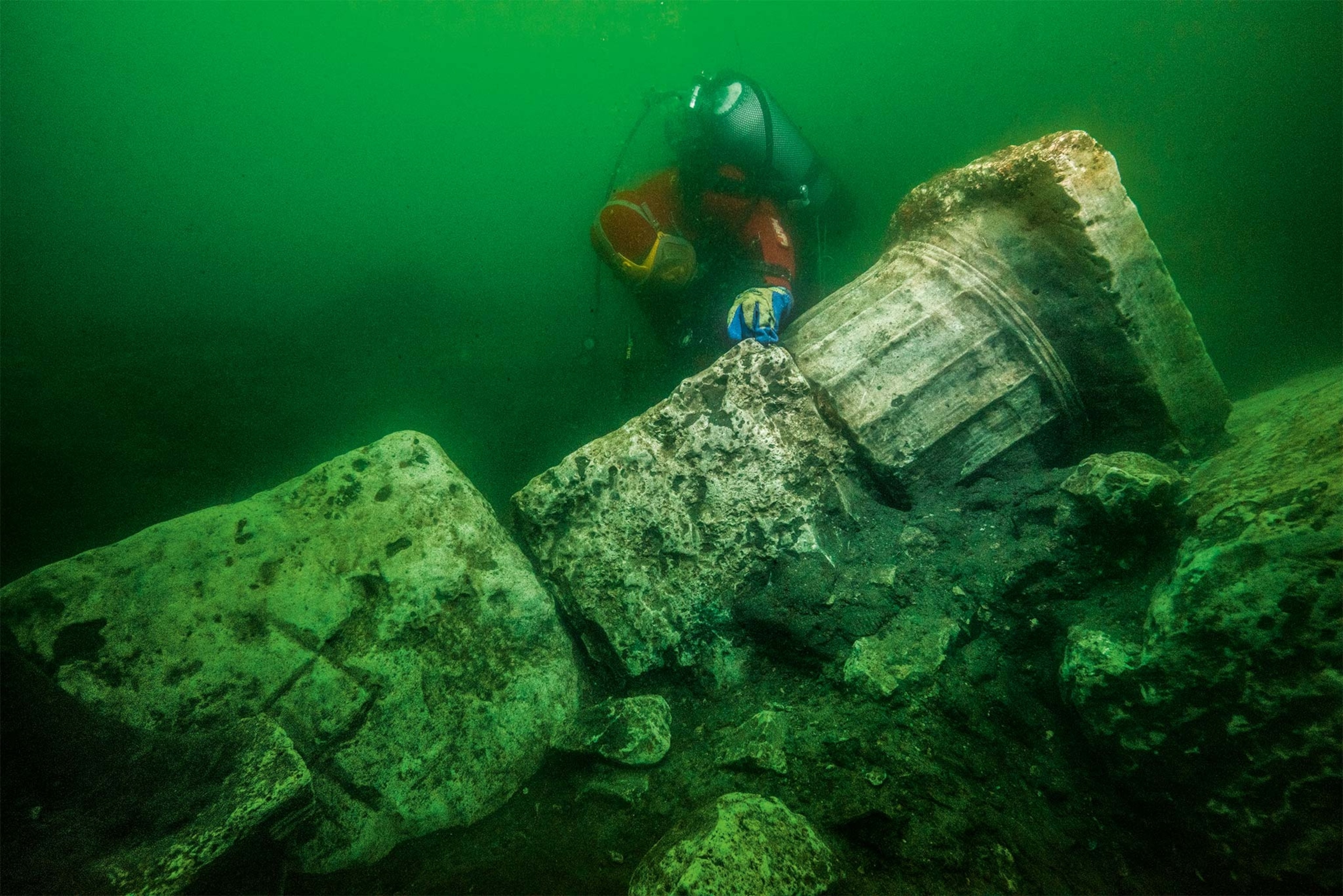 An underwater Doric column from a temple is observed by a diver