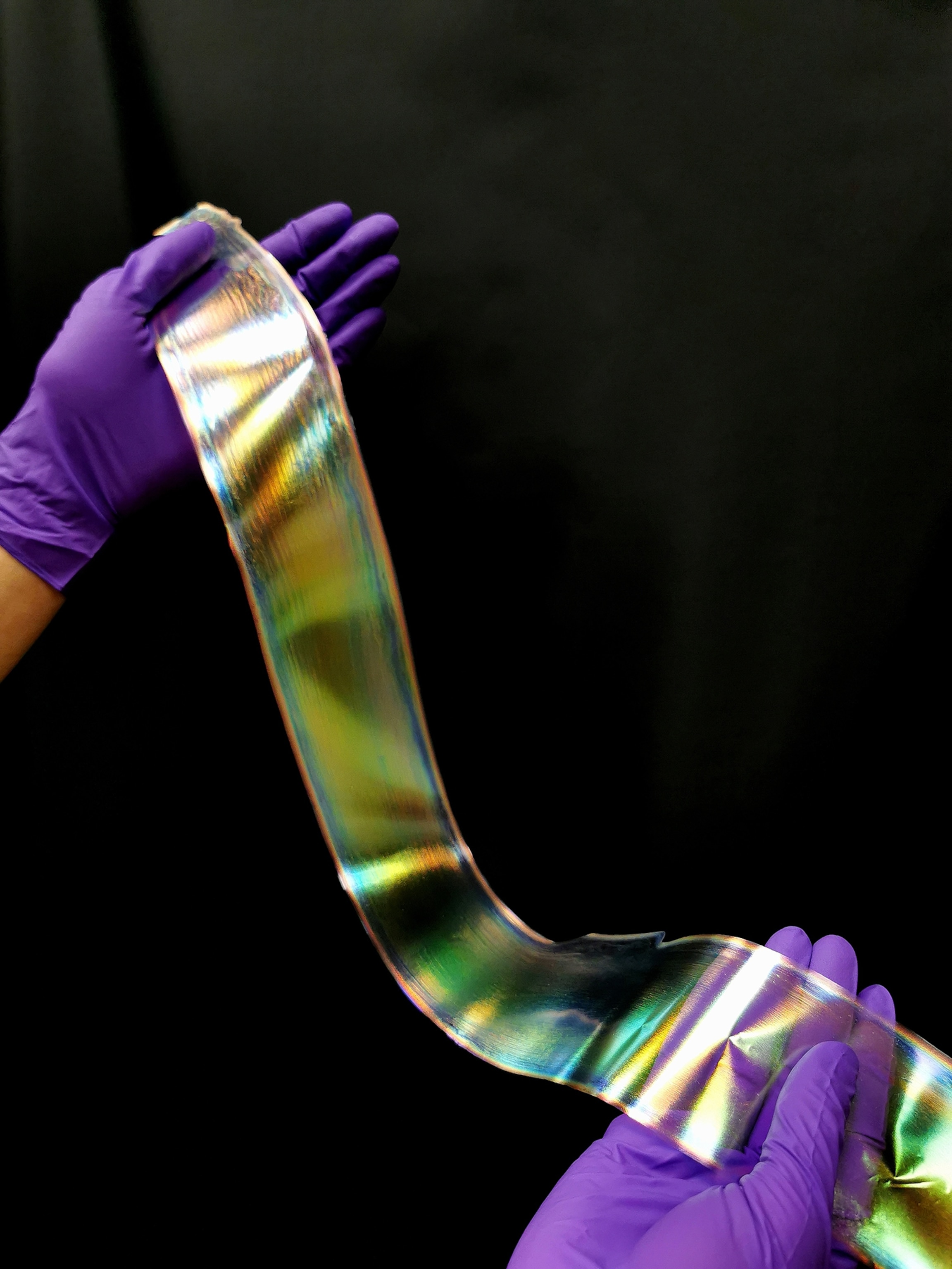 two purple gloved hands holding a luminescent strip