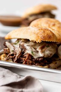 These toasty Slow Cooker French Dip Sandwiches are made with slow cooked roast beef served on crusty rolls with melty cheese and savory au jus. The prep is less than 15 minutes and then the crockpot does all the work for you. These are so good! #frenchdip #sandwiches #slowcooker #crockpot #instantpot #best #easy #shredded #beef #dinner