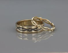 two gold wedding rings sitting side by side on a reflective surface, with one ring in the shape of a cross