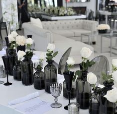 there are many black vases with white flowers in them on the table at this event