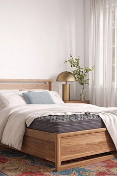 a bed with a wooden headboard and foot board in a white room next to a window