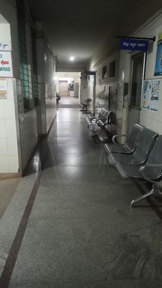 an empty hallway with metal benches and signs on the walls, in front of a door