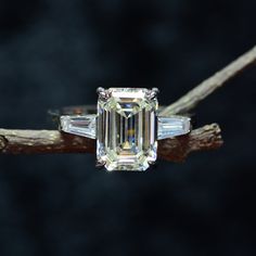 an emerald - cut diamond sits on a branch