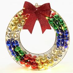 a colorful christmas wreath with a red bow on it's top and bells around the bottom