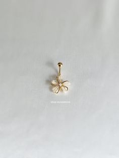 a gold nose ring with a flower on the front and back of it, sitting on a white surface