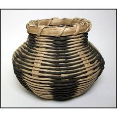 a woven basket with black and tan stripes on the bottom is sitting on a white surface