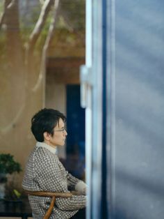 a woman sitting in a chair looking out the window