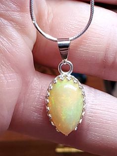 "4.00 carat green, yellow and orange natural Ethiopian opal in a Lacey bezel silver setting on a silver 18 inch chain. 5/8\" x 7/16 is the size of the stone,I will make a chain any length you like." White Gold Opal Round Necklace, White Gold Opal Necklace As Gift, White Gold Opal Necklace For Gift, Opal Gemstone Round Pendant Jewelry, Opal Gemstone Round Pendant Necklace, Teardrop Opal Gemstone Jewelry, Elegant Ethiopian Opal Pendant Necklace, Fine Jewelry Opal Oval Necklace, Teardrop Ethiopian Opal Jewelry Gift