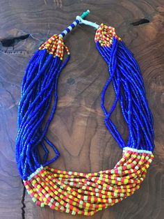 "Gorgeous vintage African glass trade bead statement necklace. It has 20 strands of glass trade beads with stunning cobalt blue, red, and yellow colors. Unique clasp featuring turquoise color beads. Necklace Measures 25\"." Artisan Multicolor Multi-strand Beads, Festival Blue Beaded Necklaces With Colorful Beads, Artisan Multicolor Multi-strand Beaded Necklaces, Artisan Multicolor Beaded Necklaces For Festivals, Hand-strung Multicolor Jewelry For Festivals, Hand-strung Multicolor Festival Jewelry, Artisan Blue Beaded Necklaces For Festivals, Multicolor Hand-strung Jewelry For Festivals, Multicolor Round Beads Necklace For Festivals