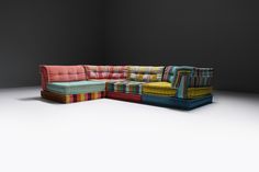 a multicolored couch sitting on top of a white floor next to a black wall