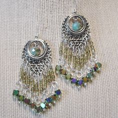 "Ornate beaded boho styling in these silver chandelier earrings. Beads are wire wrapped AB glass cube beads, green crystal beads and aqua glass beads that have an AB quality for extra shine and color. The beaded segments are linked on ornate silver metal filigree. The length of these earrings is 2 3/8\" from silver plate ear wire link. The width is 1 1/2\" at widest point on the base. Silver segment measures 1\" across. All of my jewelry items come boxed and lace ribbon tied and tagged for easy Green Beaded Bohemian Chandelier Earrings, Green Bohemian Chandelier Earrings With Dangling Beads, Bohemian Green Beaded Chandelier Earrings, Bohemian Nickel-free Beaded Drop Earrings, Nickel-free Bohemian Drop Beaded Earrings, Nickel Free Green Bohemian Chandelier Earrings, Bohemian Teardrop Beaded Fringe Jewelry, Green Bohemian Chandelier Earrings Nickel Free, Bohemian Turquoise Beaded Chandelier Earrings