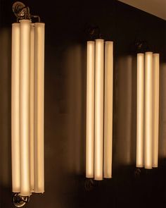 three light fixtures mounted on the wall in a room with black walls and flooring