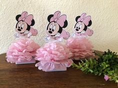 three pink tissue pom poms sitting on top of a wooden table next to flowers