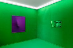 an empty room with two paintings on the wall and one in the corner that is green