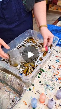 a person is painting in an art studio with lots of paint and watercolors