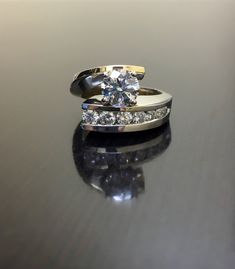 two wedding rings sitting on top of a black table next to each other with one diamond in the middle