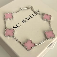 a pink bracelet with hearts on it sitting in a white box next to a name tag