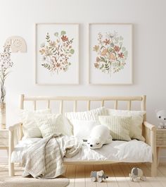 two framed pictures hang above a bed with white linens and pillows on the bed