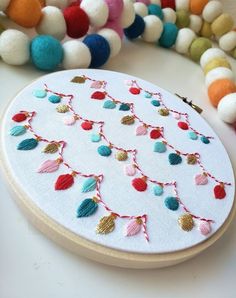 a close up of a embroidery on a table with beads and other items in the background