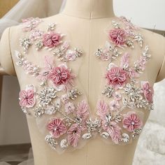 the back of a dress with pink flowers and sequins on it's shoulders