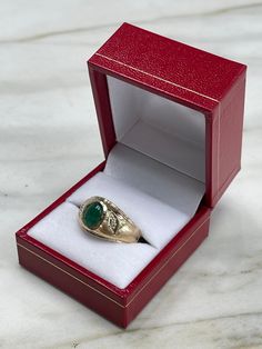 A beautiful three-stone, natural emerald cabochon, and diamond ring. The center stone cabochon has a full 1.36-carats, with a dark green color and very good luster. Accenting the cabochon are two petite brilliant round diamonds. This one-of-a-kind ring is in 10K yellow gold, with a satin finish going halfway down the band giving it the perfect touch. Setting Style: Three-Stone Setting Material: 10K Yellow Gold Gold Weight: 5.8 Grams Main Stone: Emerald Cabochon Shape: Oval Cut Weight: 1.36-Carat Emerald Oval Cabochon Ring As A Gift, Classic Marquise Emerald Ring In Gold, Classic Gold Marquise Emerald Ring, Heirloom Oval Cabochon Emerald Ring, Formal Fine Jewelry Signet Ring With Cabochon, Formal Cabochon Signet Ring, Emerald Bezel Set Oval Cabochon Ring, Heirloom Gold Emerald Ring With Oval Cabochon, Oval Signet Ring With May Birthstone Gemstone