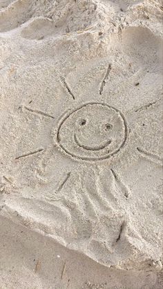 a smiley face drawn in the sand on a beach