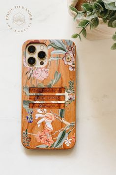 an iphone case with flowers on it next to a plant