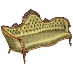 an antique style couch with green upholstered fabric and wood trimmings on it