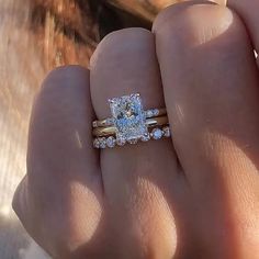 a close up of a person's hand with two rings on their fingers and an engagement ring in the other hand