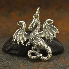 a silver dragon charm sitting on top of a rock