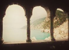 an arch in the side of a building looking out at water and mountains on both sides