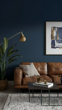 a living room with blue walls and leather couches in the corner, coffee table on rug