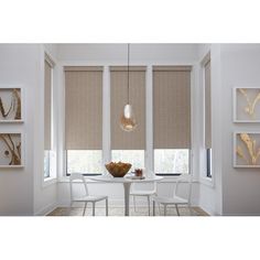 a dining room with white walls and windows covered in blinds that are open to the outside