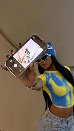 a woman taking a selfie with her cell phone while wearing a yellow and blue shirt