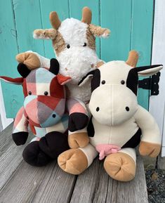 three stuffed animals are sitting on a wooden bench together, one is white and the other is brown