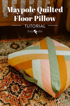 a colorful pillow sitting on top of a rug next to a crib with the words, maypole quilted floor pillow