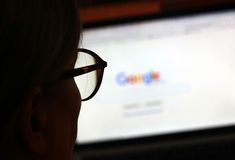 a close up of a person wearing glasses looking at a computer screen with the google logo on it