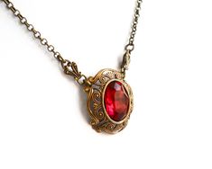 Beautiful victorian style pendant necklace made of a lovely oxidized brass filigree cabochon base, American made, and a vintage ruby red rhinestone cabochon. The size of the cabochon is 13 x 18 mm. The necklength is approximately 49 cm. (19.3 inches) For more jewelry please visit our shop: http://www.minouc.etsy.com For combined shipping please contact us. We also combine shipping with our other Etsy shop where we sell vintage fabrics and finds from Holland and France: http://www.minoucbrocante. Elegant Red Locket Necklaces, Antique Red Jewelry For Gifts, Victorian Antique Gold Necklaces For Valentine's Day, Victorian Antique Gold Necklace For Valentine's Day, Antique Brass Necklaces For Valentine's Day, Antique Brass Jewelry For Valentine's Day, Victorian Ruby Pendant Jewelry, Antique Red Pendant Jewelry, Red Ruby Victorian Necklace