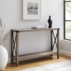 a white vase sitting on top of a wooden table next to a framed photo and a black and white vase