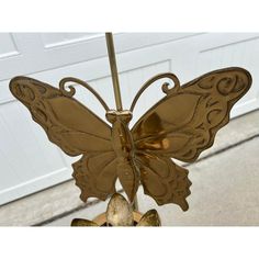 a gold butterfly wind chime hanging from a pole in front of a garage door