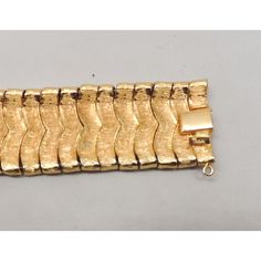 This is part of Chairish’s Costume Jewelry assortment.  Goldtone textured and smooth Asian inspired "waves" articulated bracelet with box clasp and security chain. Marked crown "TRIFARI." Measures: 7 1/4 inches long by 1 inch wide. Condition: Very good; light surface wear in places and a spot of goldtone loss to the back of part of the box clasp. An identical bracelet was featured in a 1959 advertisement. Elegant Gold Snake Chain Bracelet For Formal Occasions, Formal Snake Chain Bracelet, Elegant Formal Gold Snake Chain Bracelet, Elegant Formal Chain Bracelet, Formal Metal Bracelet With Rectangular Links, Gold Jubilee Bracelet With Snake Chain For Formal Occasions, Gold Metal Bracelet For Formal Occasions, Formal Gold Snake Chain Jubilee Bracelet, Formal Gold Jubilee Bracelet With Snake Chain