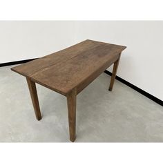 a wooden table sitting on top of a floor next to a white wall in a room