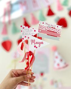 a hand holding two red and white flags with hearts hanging from the ceiling behind them