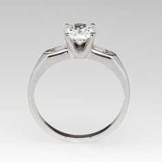 This gorgeous circa 1950s engagement ring is centered with a round transitional cut diamond weighing 1.01 carats and set into a four-prong head. The shoulders of the ring are each accented with a baguette cut diamond and a round single cut diamond. The ring measures 6.4mm at the top and rises 5.9mm above the finger. The ring is currently a size 7.25 and we offer complimentary resizing to fit. Gia Certified Moissanite Diamond Ring Marquise Cut, Classic Diamond White Diamond Ring With Tension Setting, Vintage Round Cut Diamond Ring With Tension Setting, Classic White Diamond Ring With Tension Setting, Gia Certified Timeless Marquise Cut Wedding Ring, Brilliant Cut Classic Promise Ring, Classic White Gold Diamond Ring With Tension Setting, Brilliant Cut Classic Style Promise Ring, Platinum Solitaire Diamond Ring Round Cut