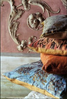 four pillows stacked on top of each other in front of a wall with an ornate design